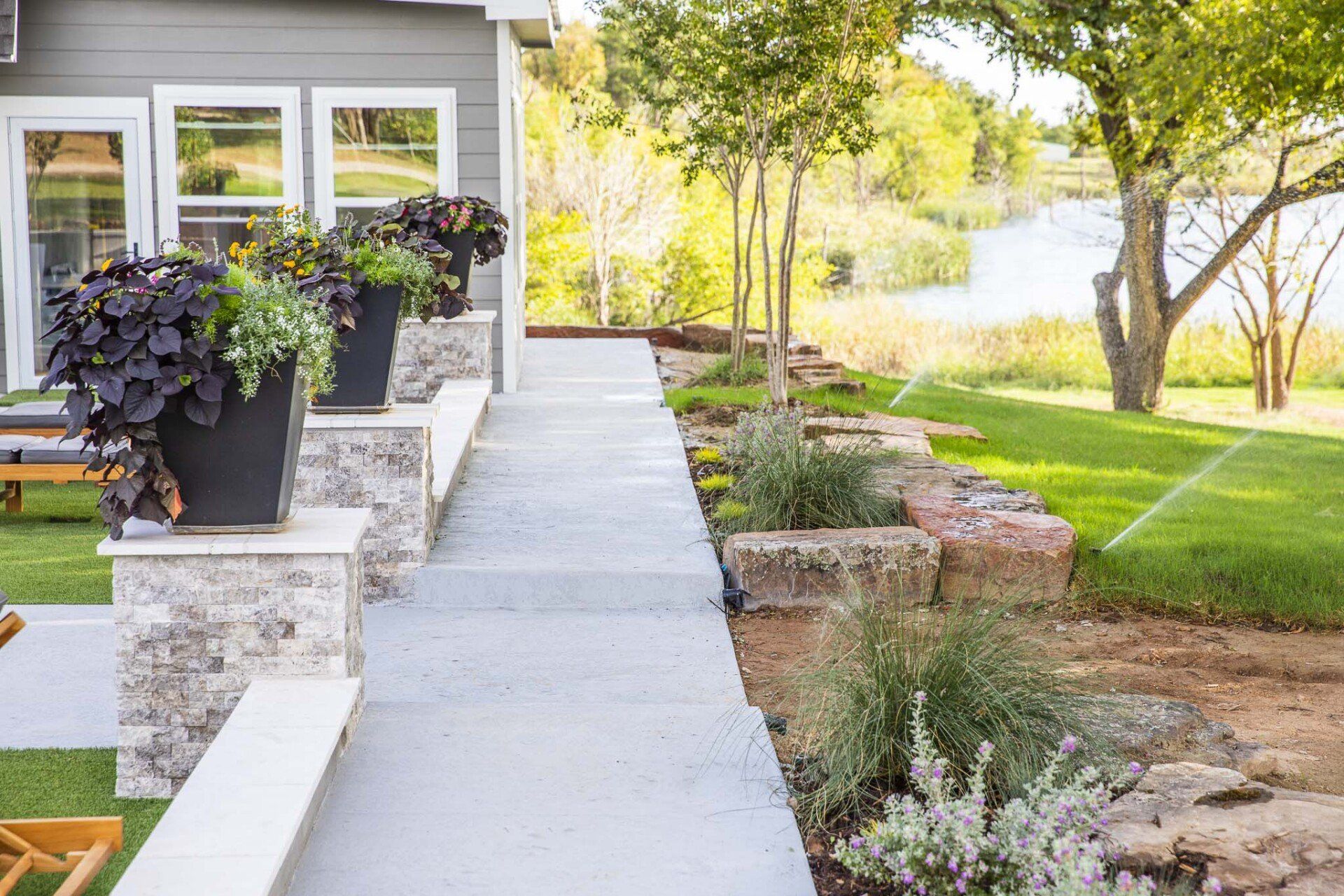 A walkway leading to a house with potted plants on the side of it.