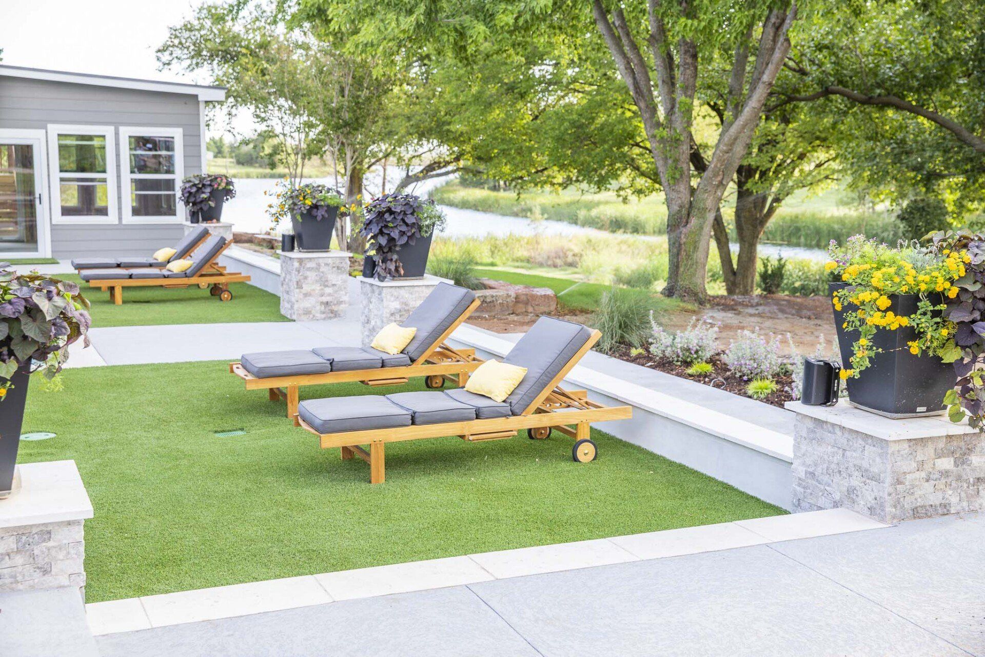 A row of lounge chairs are sitting on top of a lush green lawn.