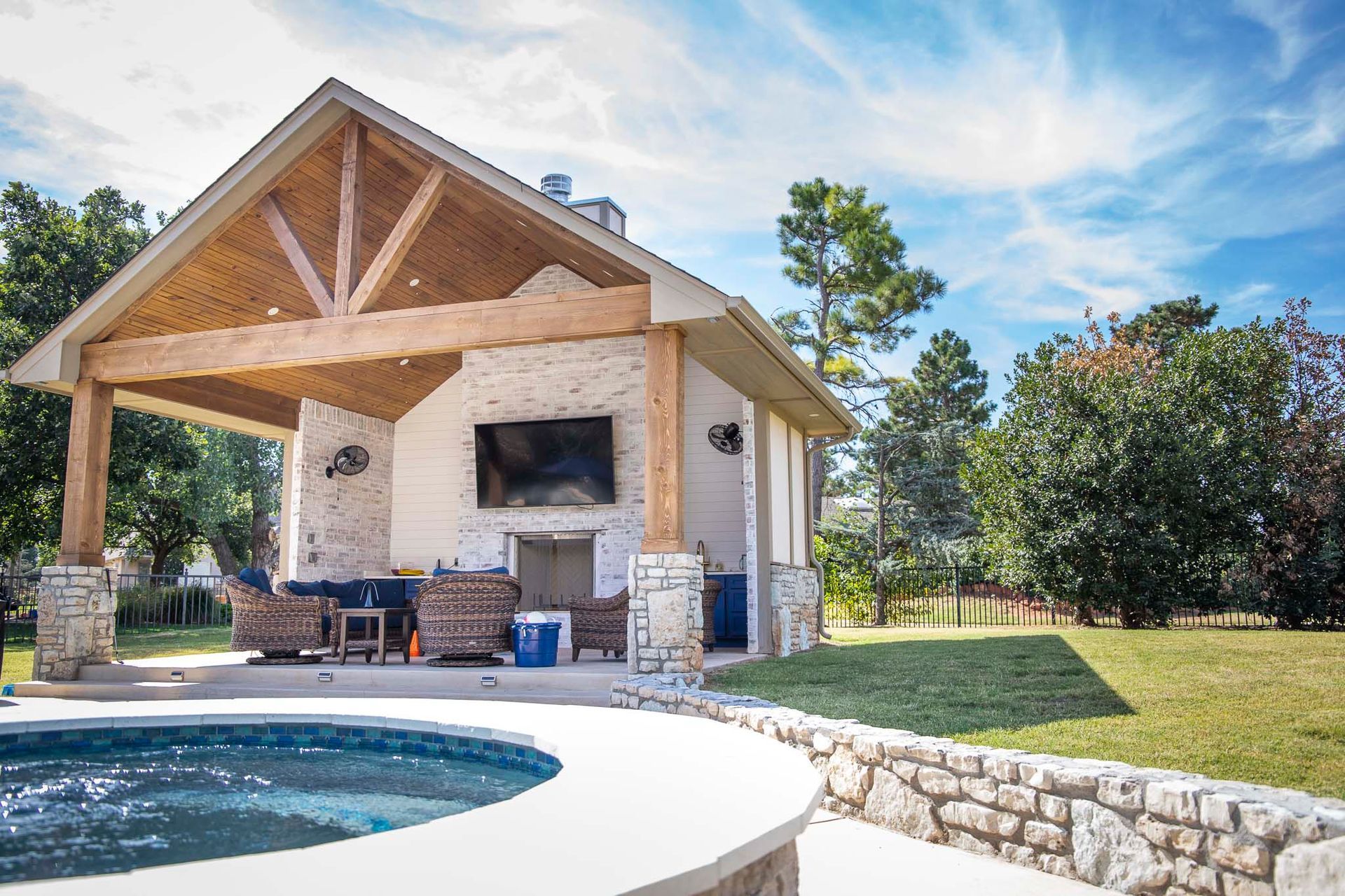 A large house with a covered patio and a pool in front of it.