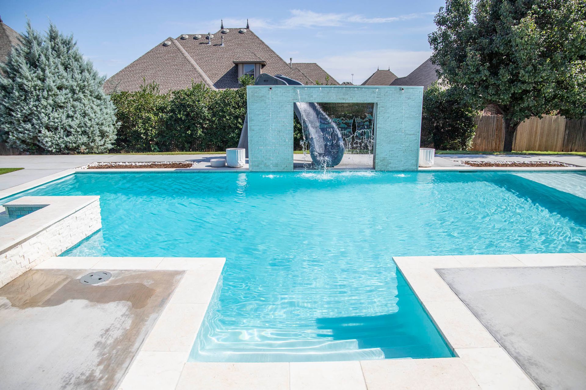 A large swimming pool with a water slide in the backyard of a house.