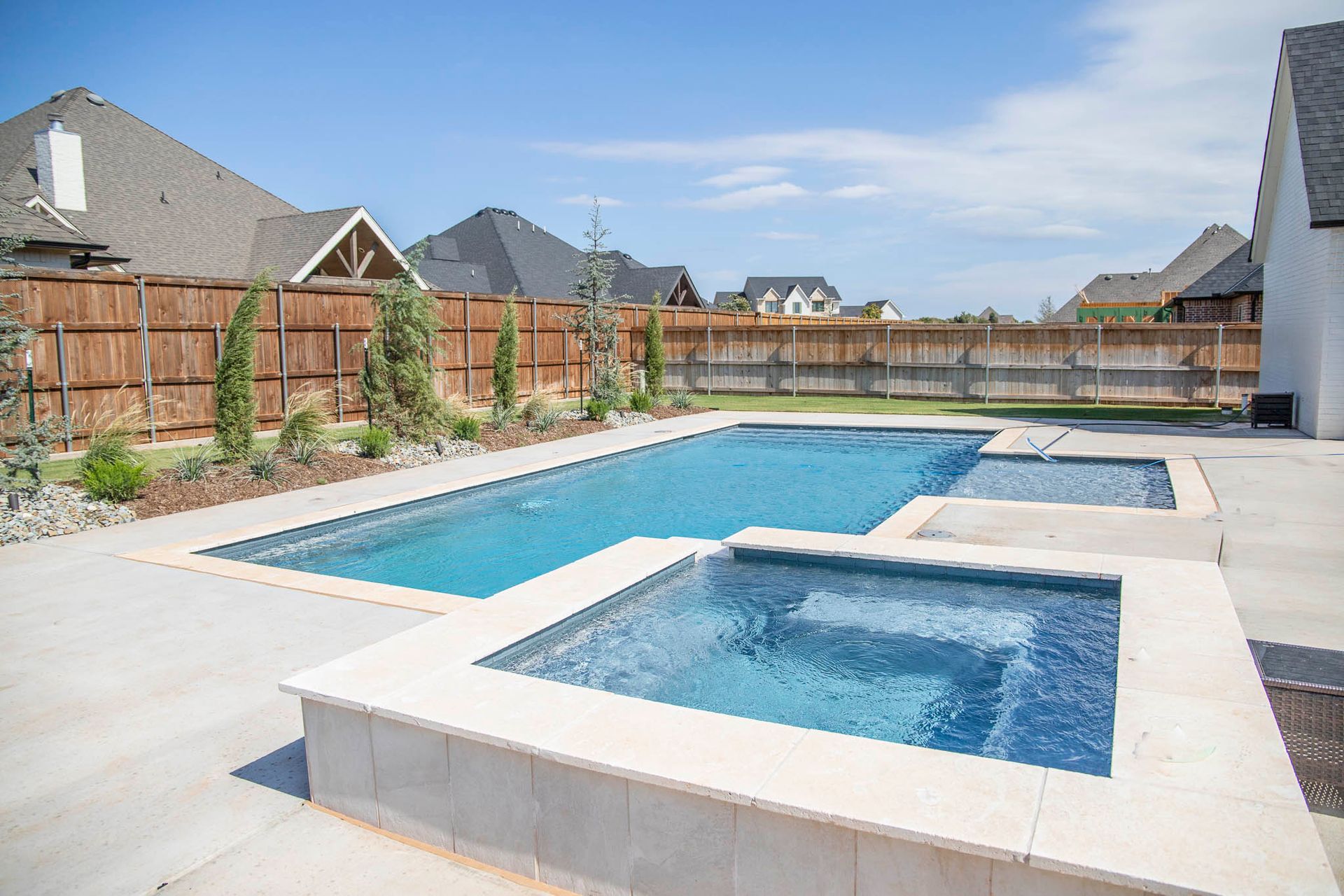 A large swimming pool with a hot tub in the backyard of a house.