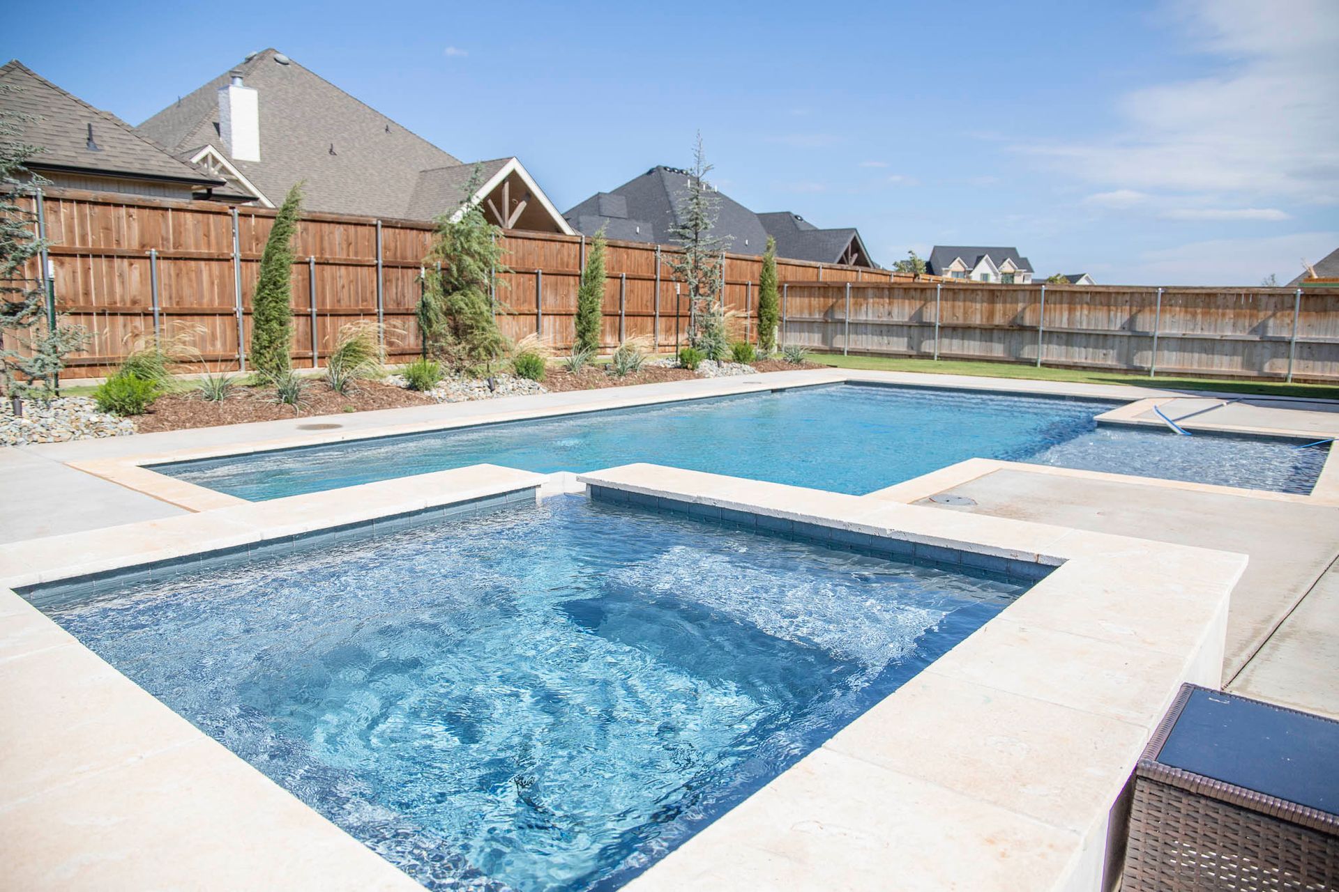 A large swimming pool and a hot tub in a backyard.