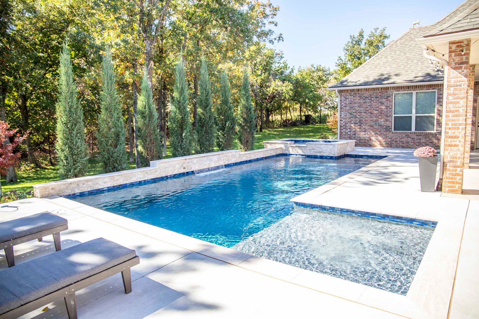 There is a large swimming pool in the backyard of a house.