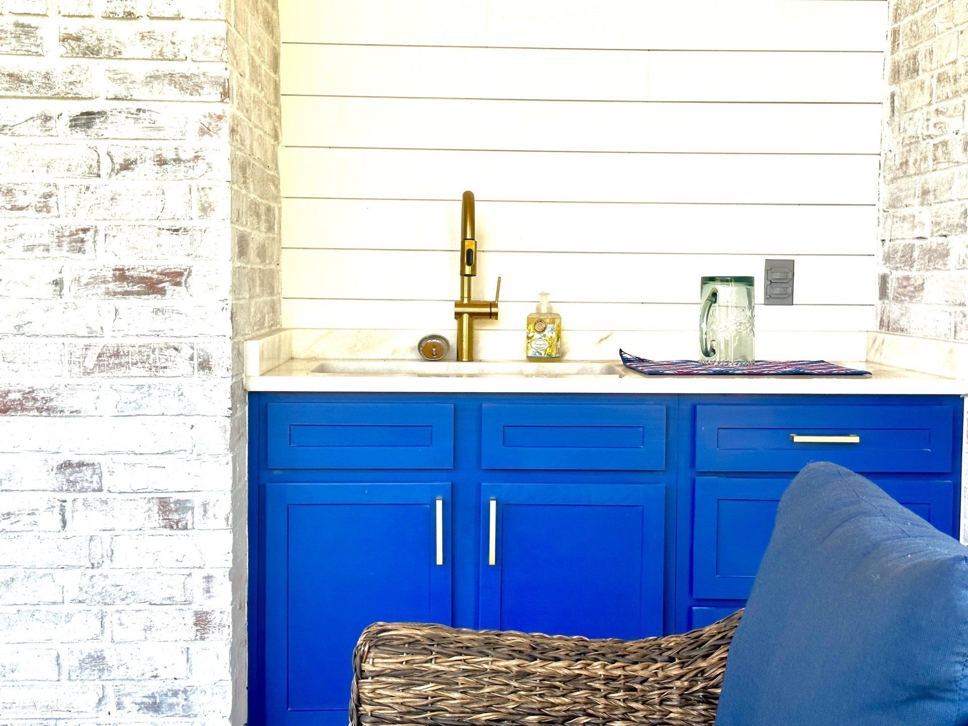 A kitchen with blue cabinets and a wicker chair.
