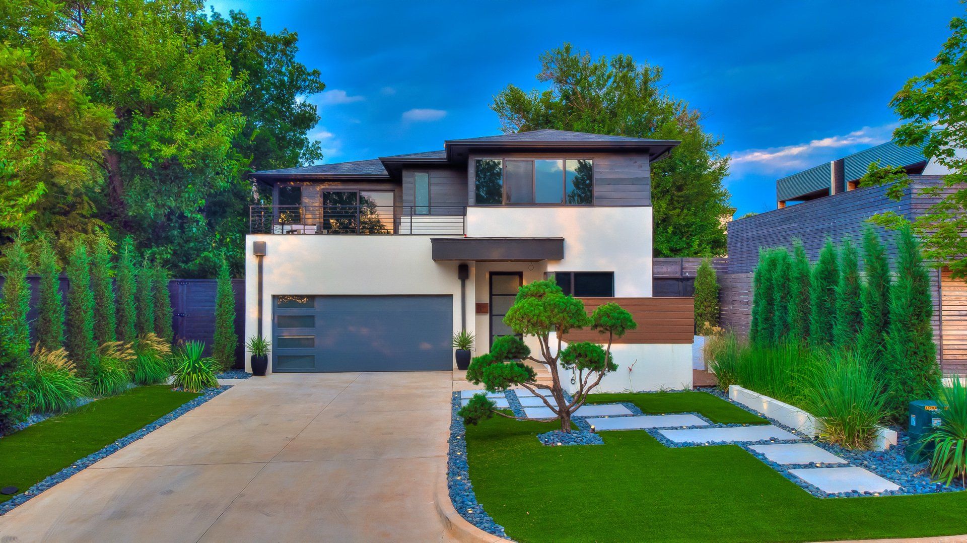 A modern house with a large driveway and a lush green lawn