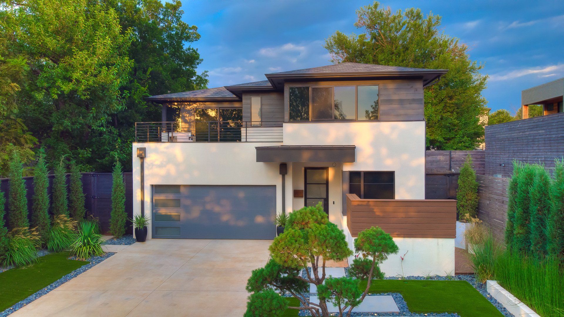 A modern house with a large garage and a lush green lawn.