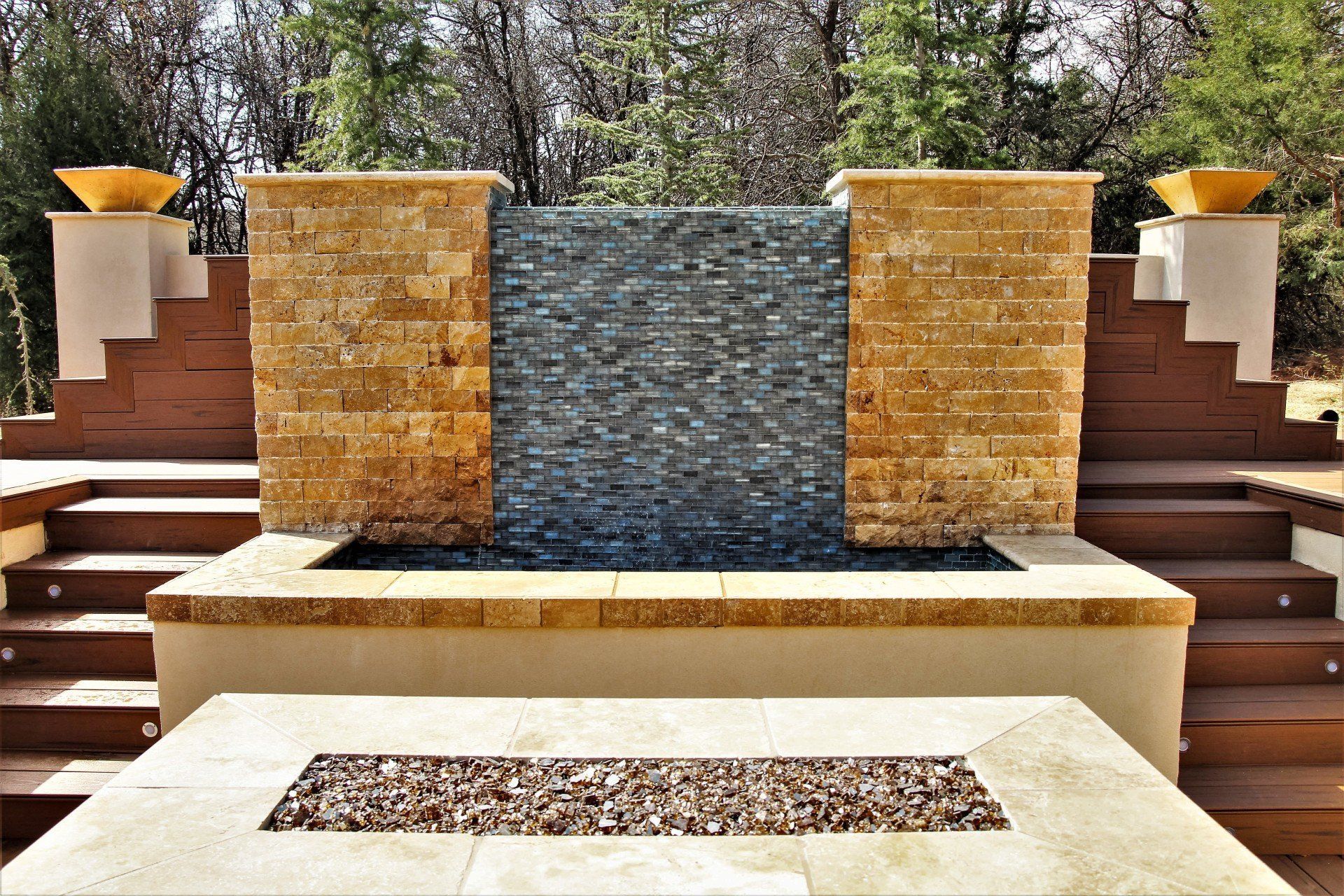 A waterfall is surrounded by stairs and a fire pit