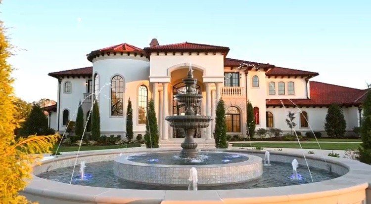 A large house with a fountain in front of it.