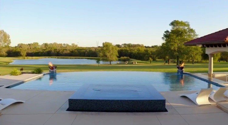 A large swimming pool with a gazebo in the background and a lake in the background.