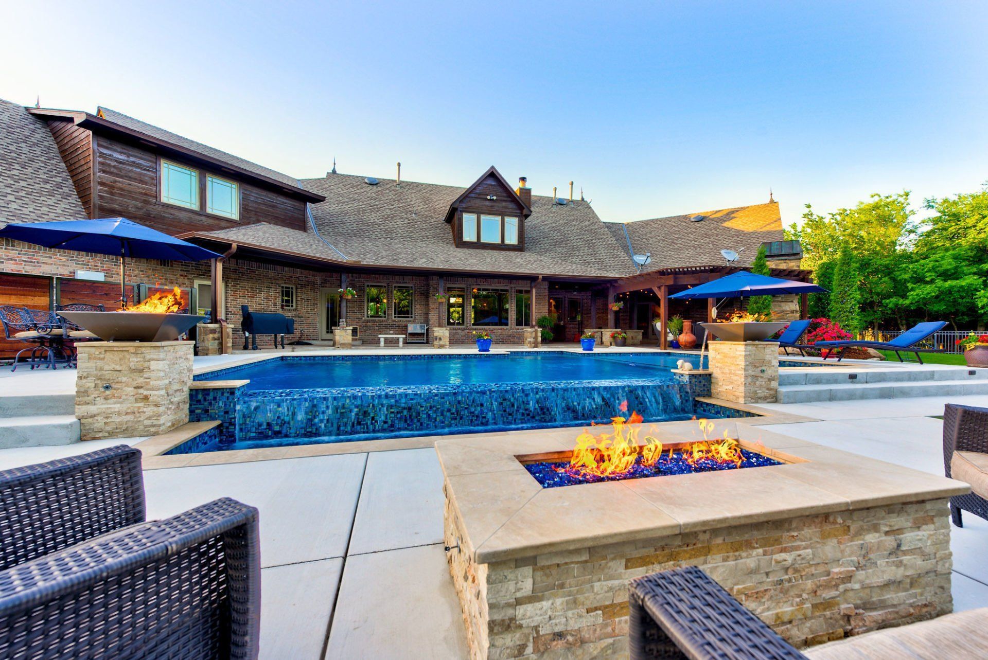 There is a fire pit in the middle of the patio in front of a large house.