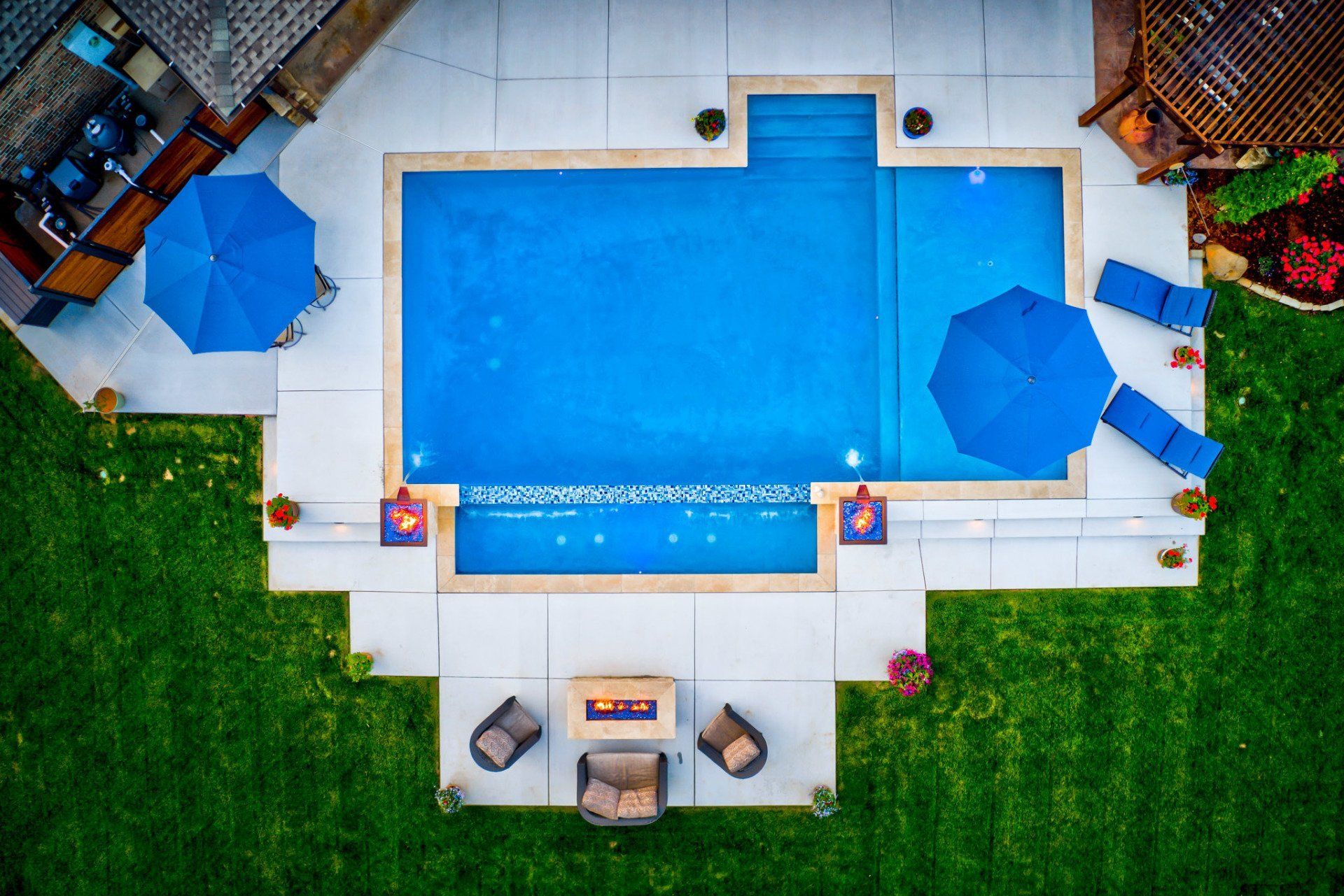 An aerial view of a large swimming pool with blue umbrellas