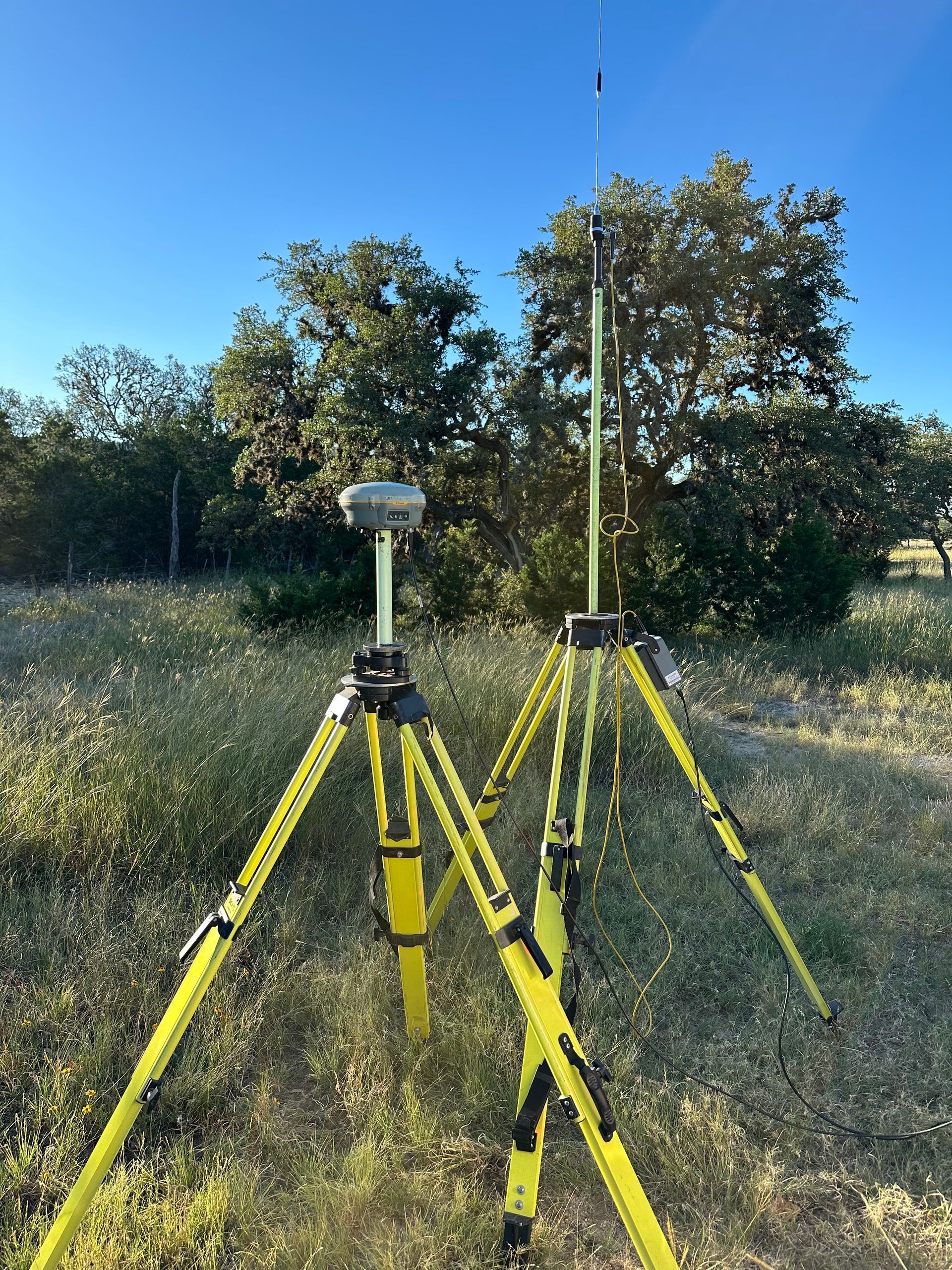 Two tripods are sitting in a field with trees in the background.