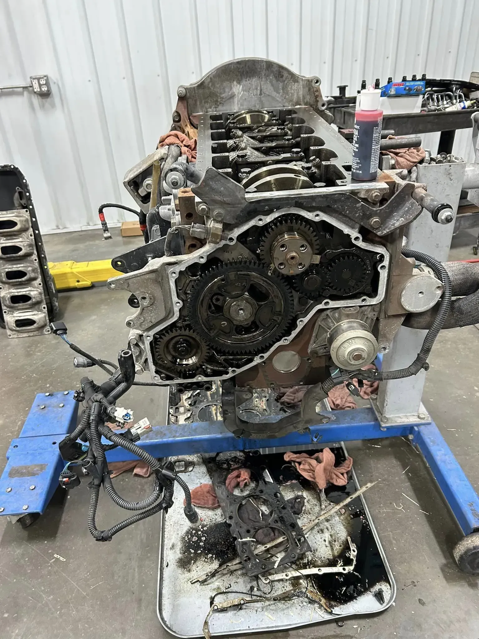 A partially disassembled engine mounted on a blue stand in a workshop, with internal gears and components exposed.