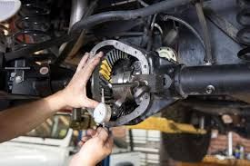 A mechanic uses a dial indicator to measure the backlash on an automotive differential ring gear.