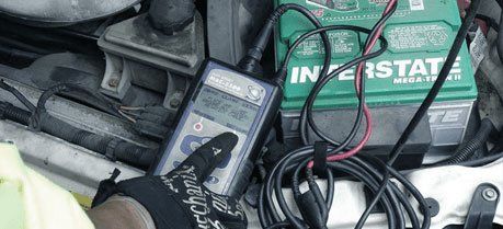 Mechanic uses a voltmeter to check the voltage level in a car battery