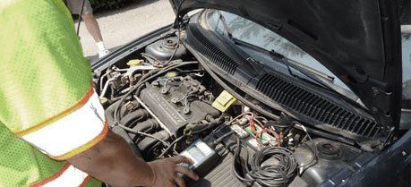 Mechanic uses a voltmeter to check the voltage level in a car battery