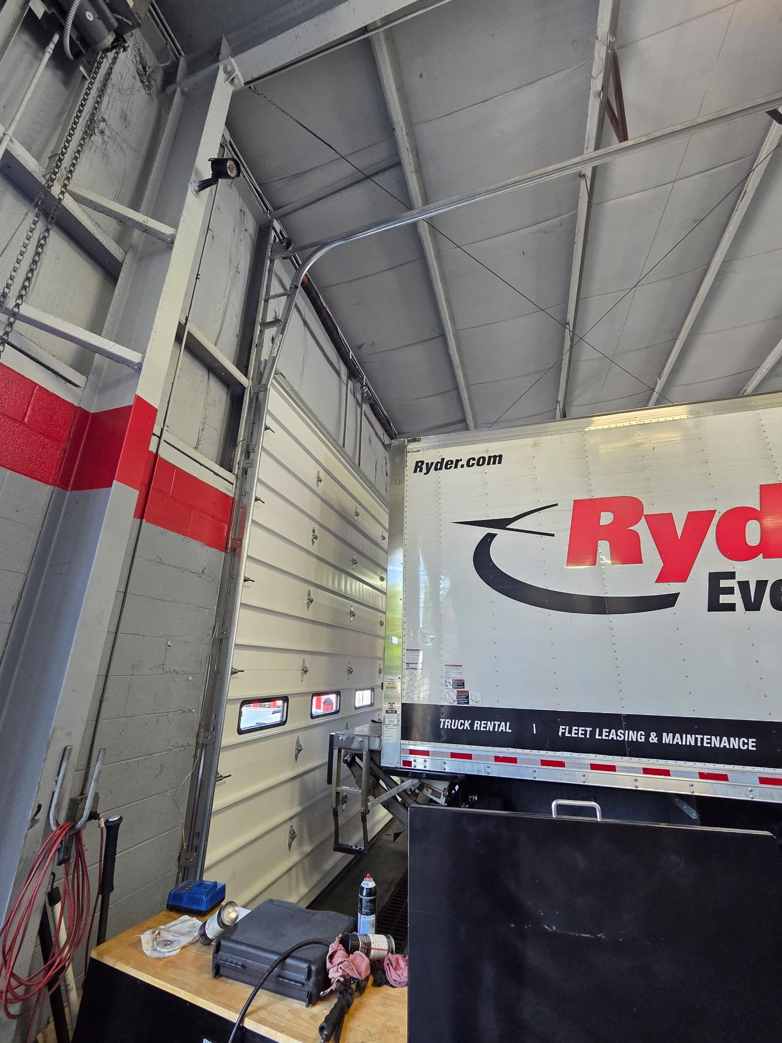 Ryder truck backed into a loading dock with a partially open garage door.