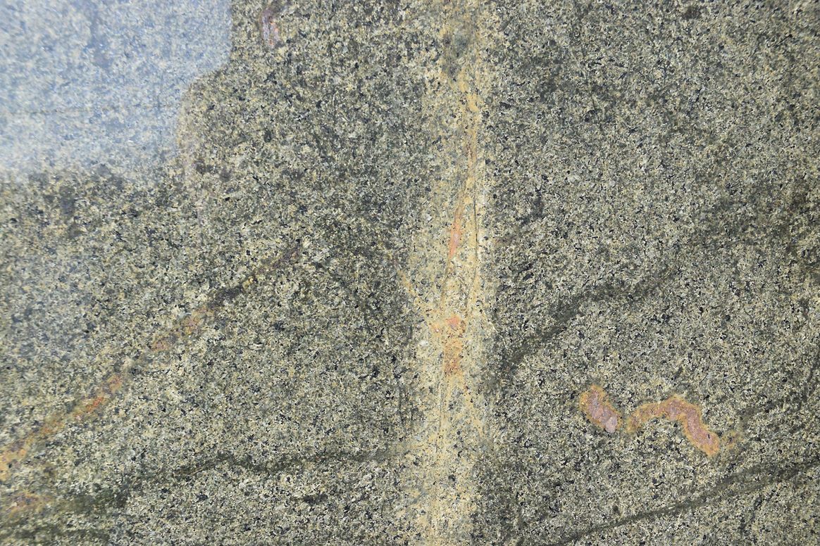 A close up of a piece of granite with a few small stones on it.