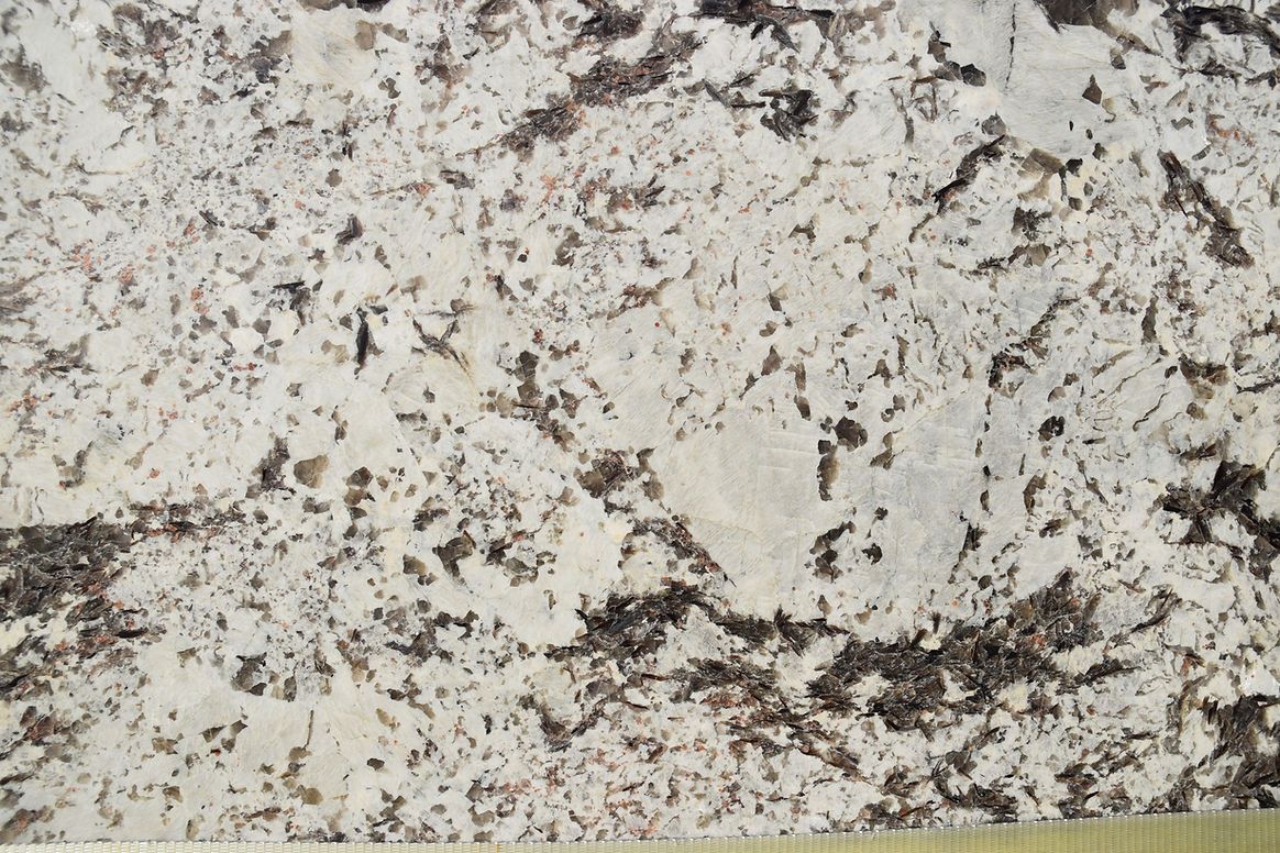 A close up of a white granite counter top with black spots