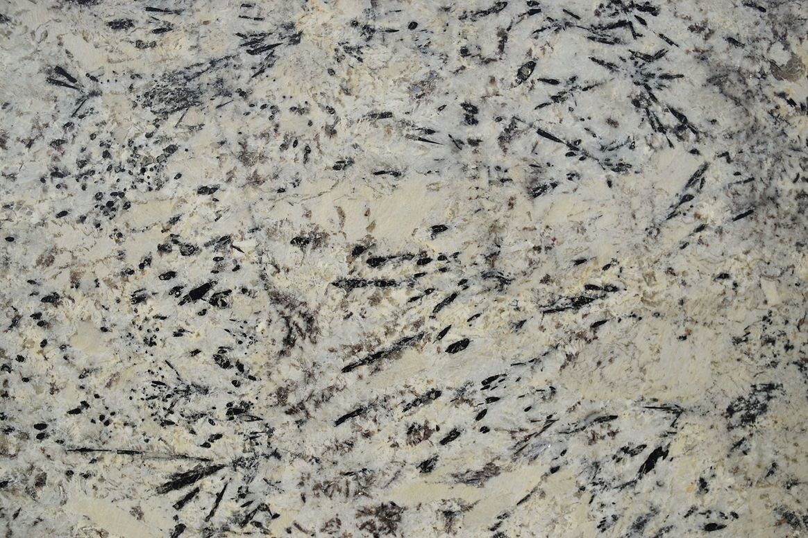 A close up of a white granite counter top with black spots