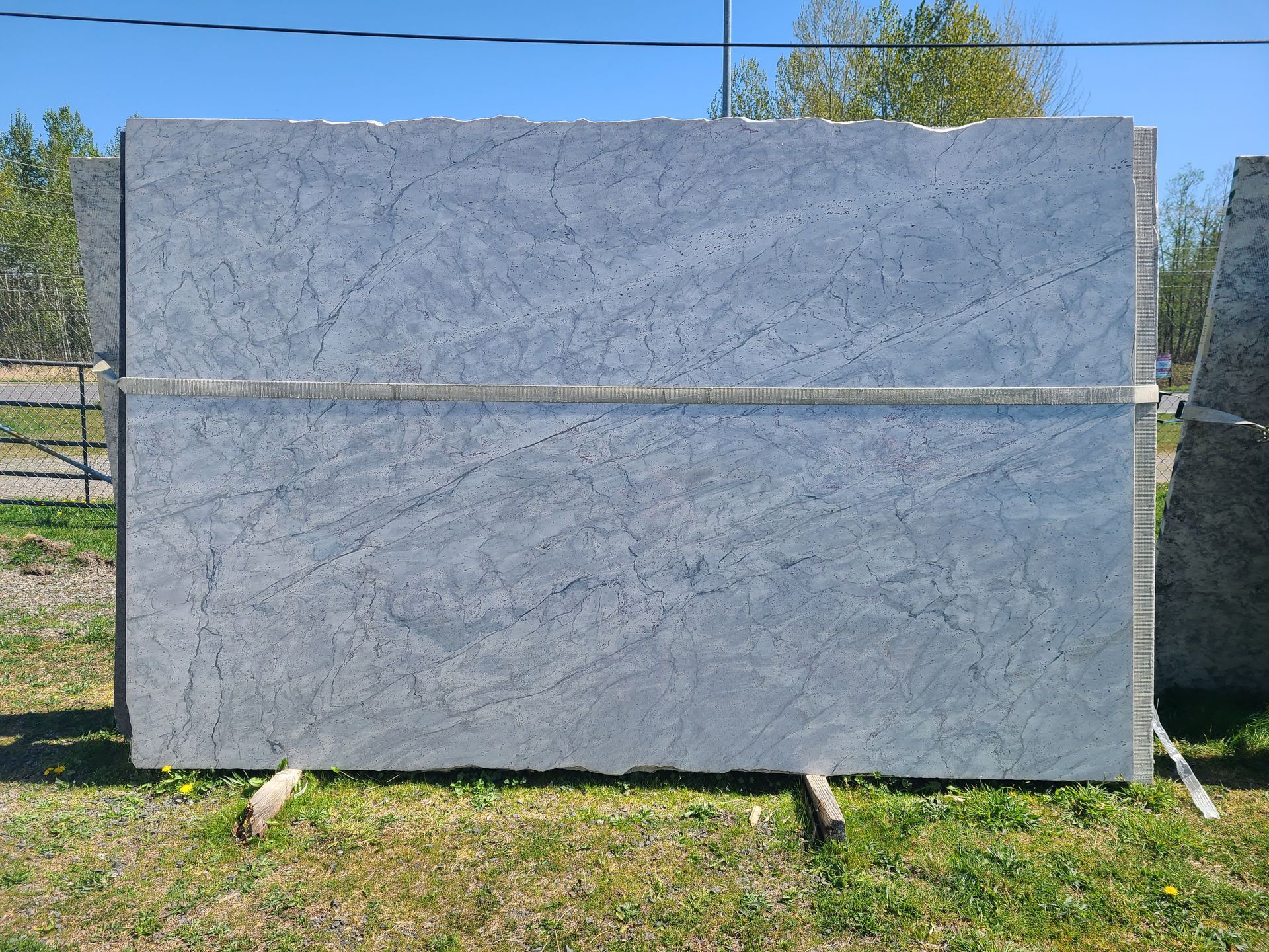 A large slab of granite is sitting on a wooden stand in the grass.