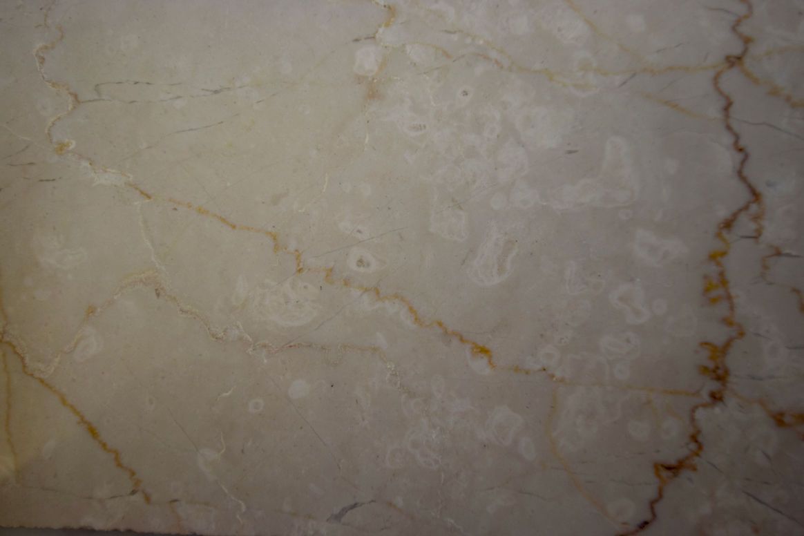 A close up of a white marble tile with a yellow vein.