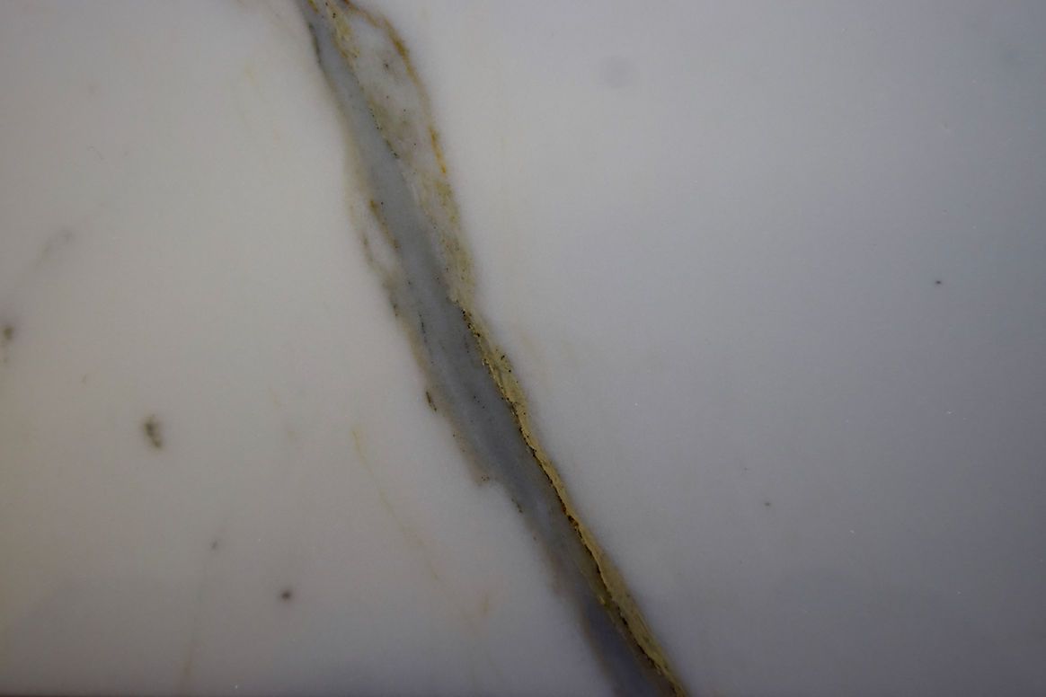 A close up of a piece of white marble with a yellow stripe on it.