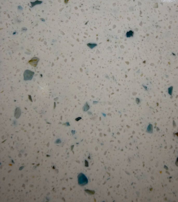 A close up of a white surface with blue and green stones