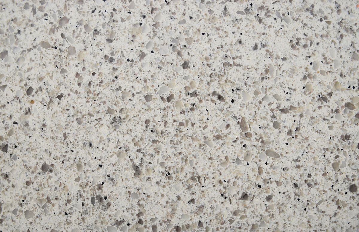 A close up of a white granite counter top with gray spots.