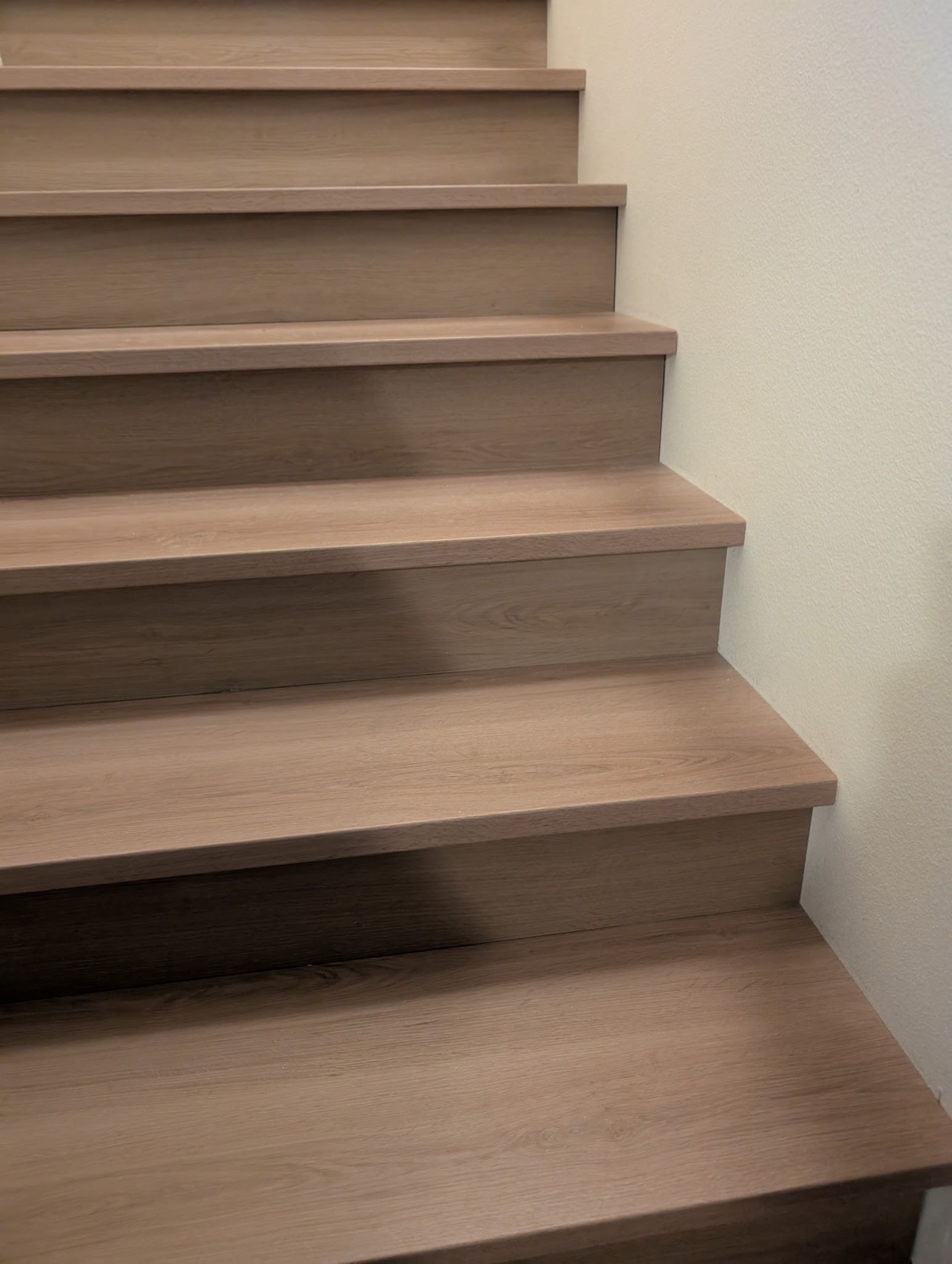 Wooden staircase against a beige wall, ascending.