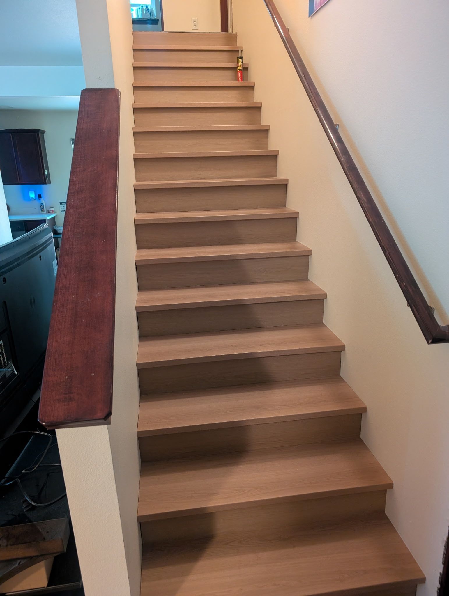 Wooden staircase with a dark brown handrail.
