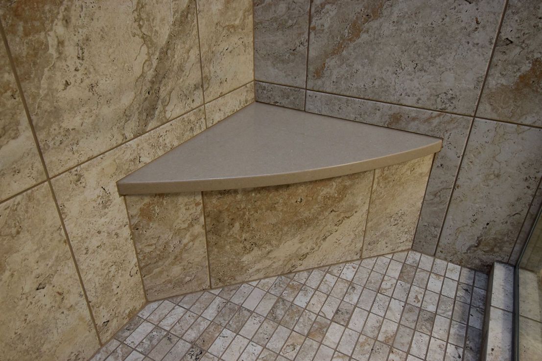 There is a corner bench in the shower.