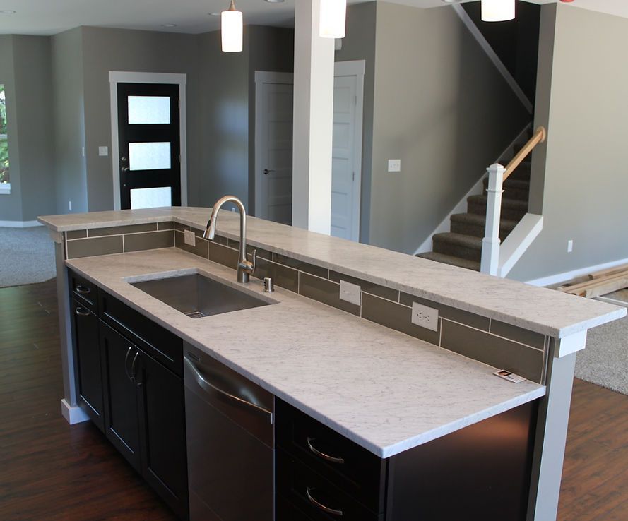 A kitchen with a sink and stairs in the background