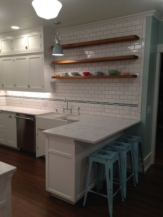 A kitchen with white cabinets and blue stools and a sink