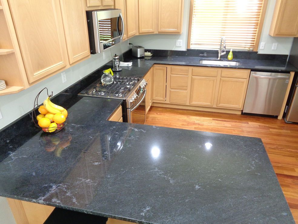 A kitchen with a black counter top and wooden cabinets