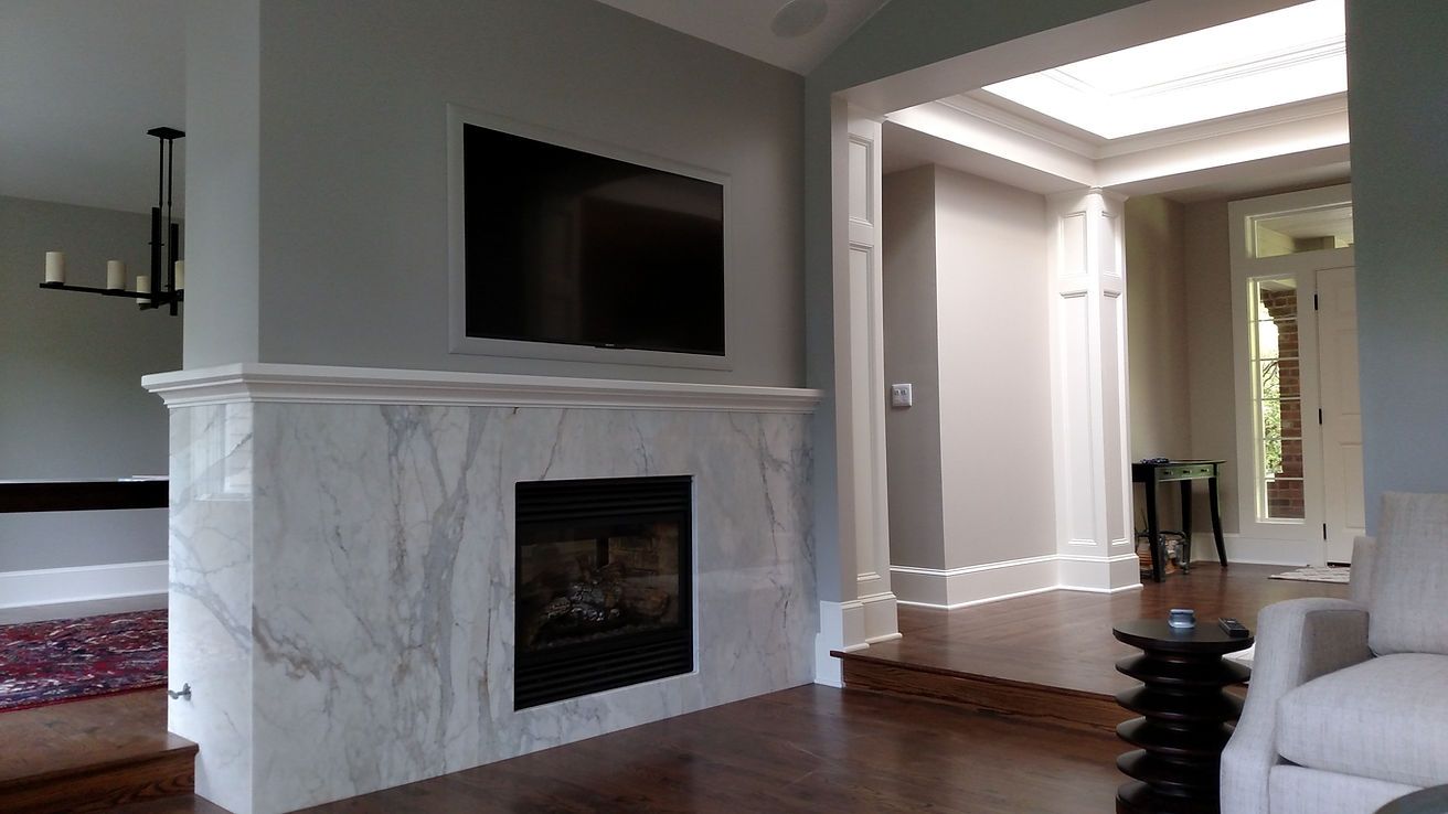 A living room with a fireplace and a flat screen tv on the wall.
