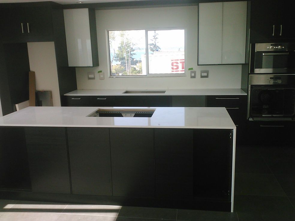 A kitchen with black cabinets and white counter tops