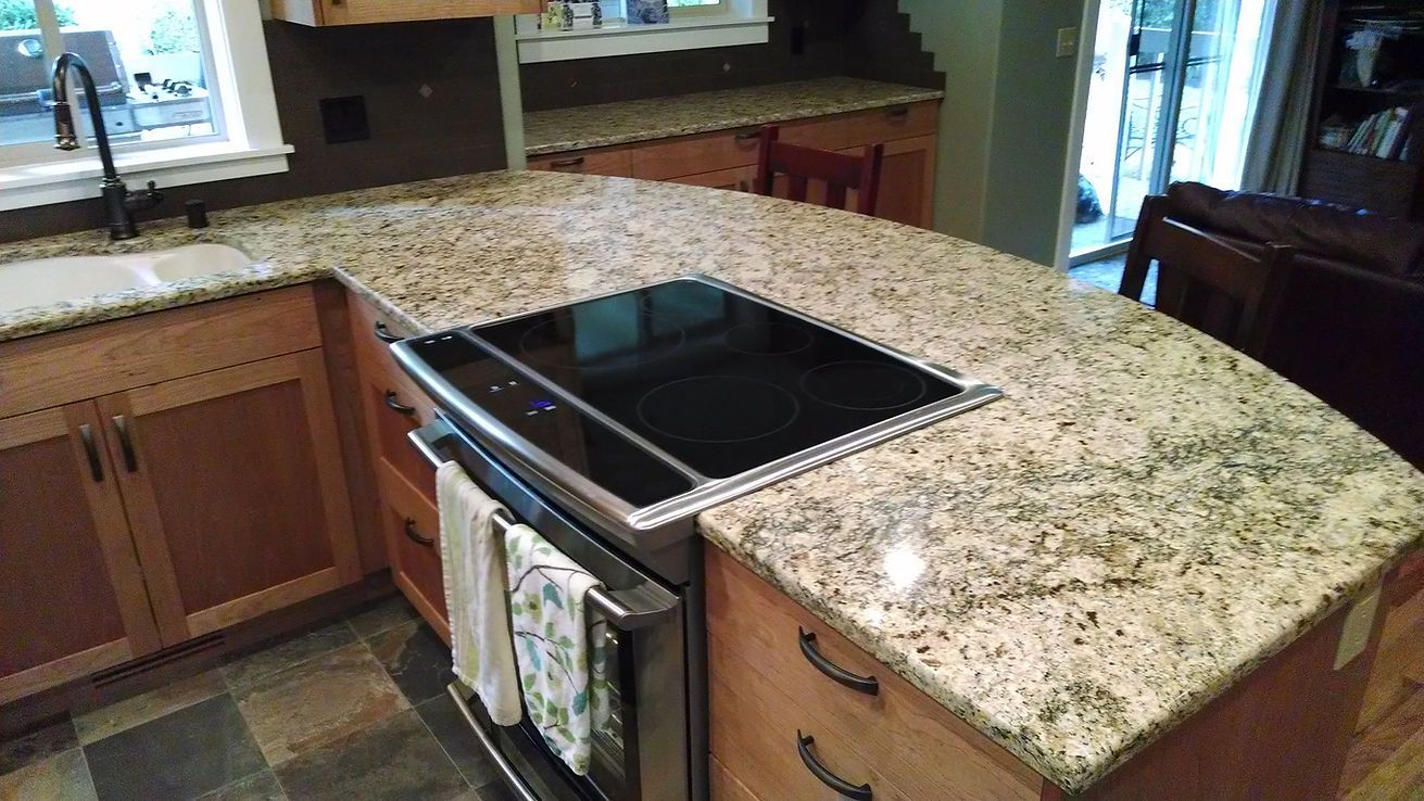 A kitchen with granite counter tops and a stove top oven.