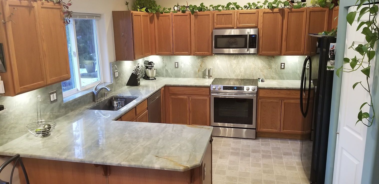 A kitchen with wooden cabinets , granite counter tops , stainless steel appliances , and a stove.