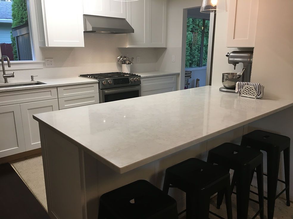 A kitchen with white cabinets , a stove , a sink , and a large island.