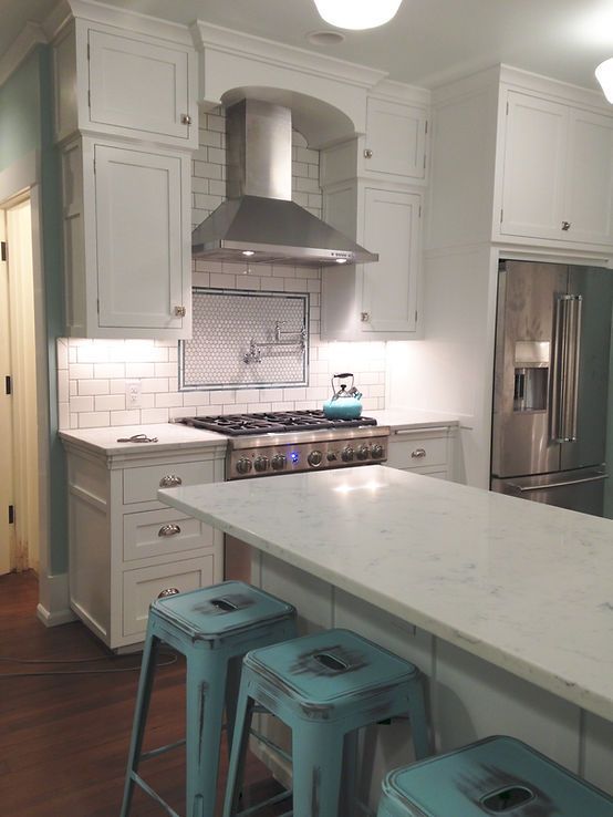 A kitchen with white cabinets and blue stools
