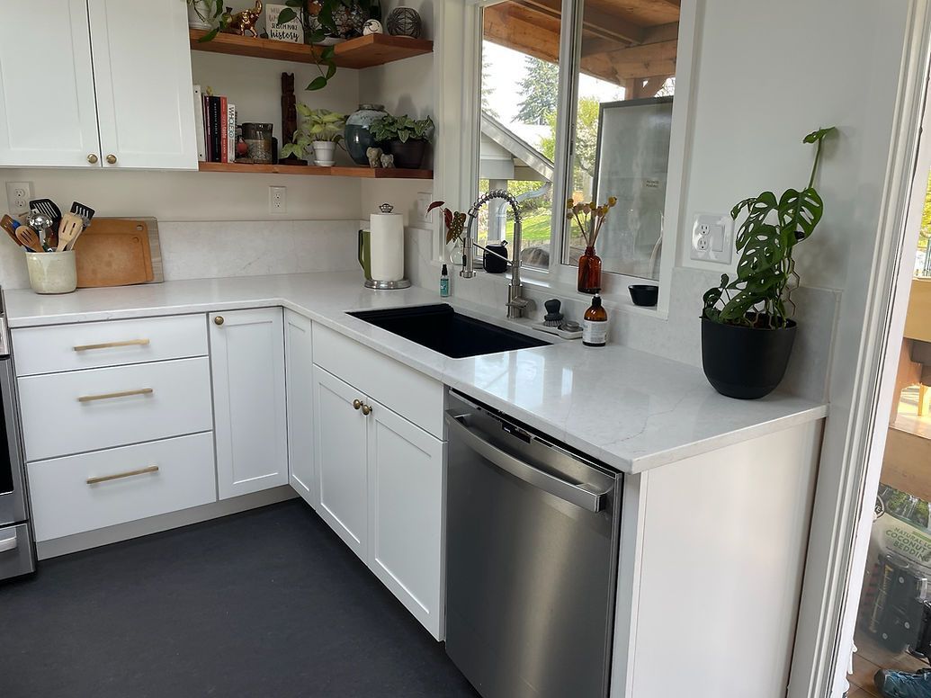 A kitchen with white cabinets , a sink , and a stainless steel dishwasher.