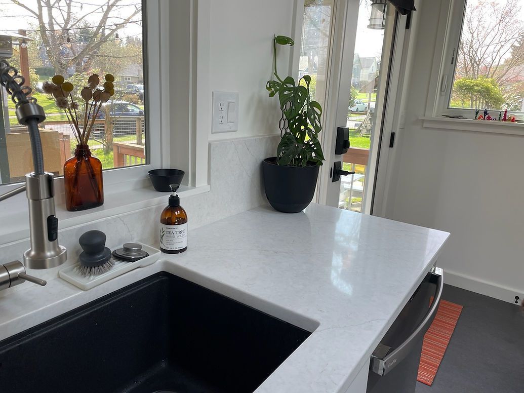 A kitchen with a black sink and a white counter top.