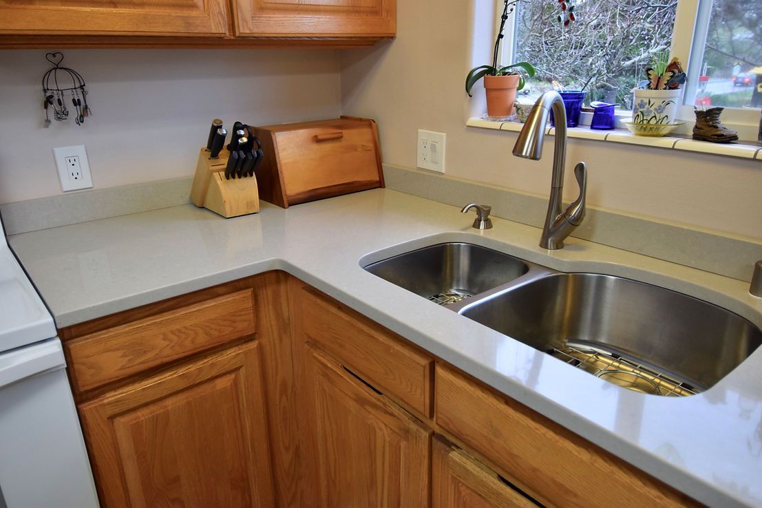 A kitchen with a stainless steel sink and wooden cabinets
