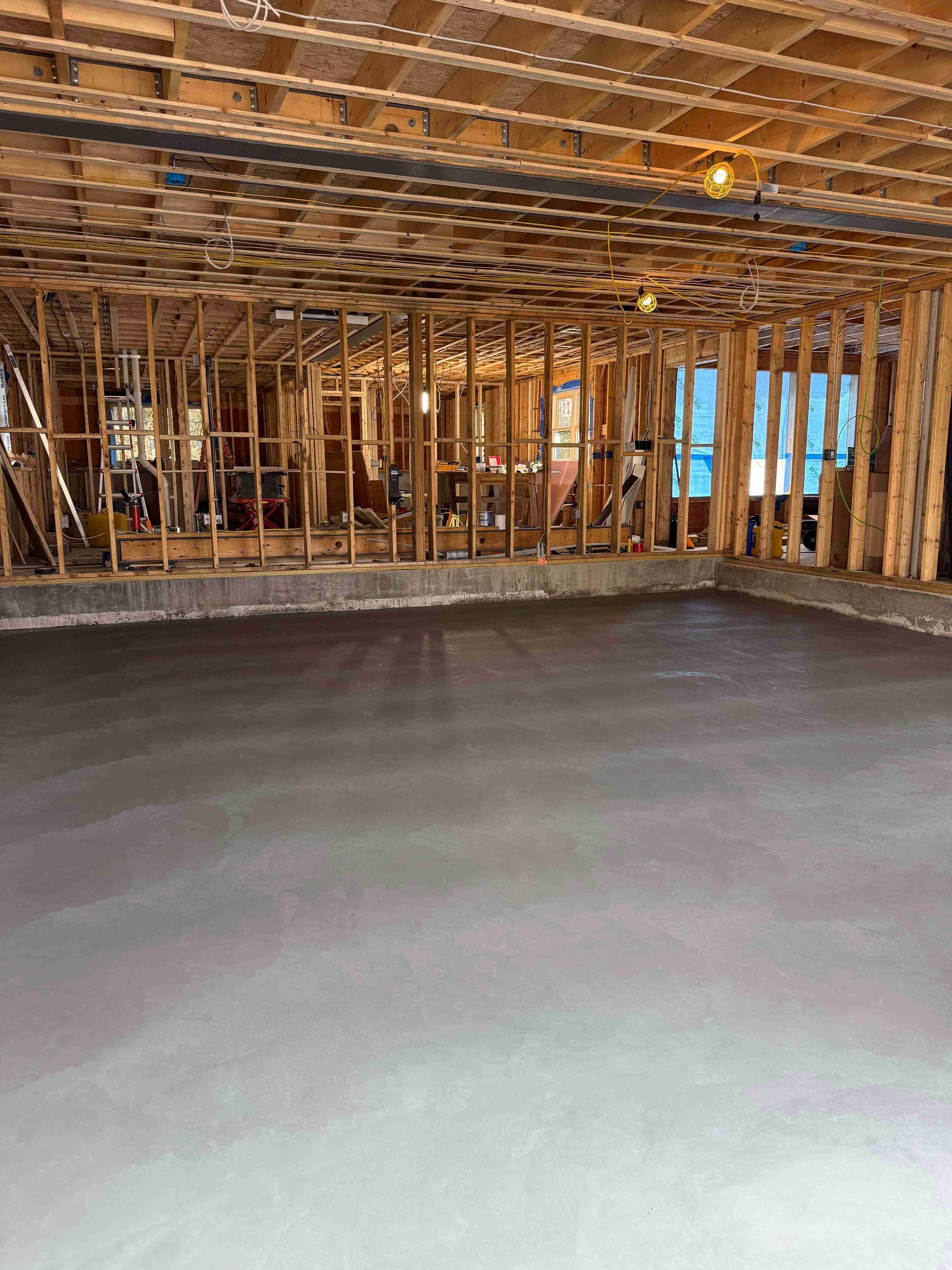 Unfinished basement with concrete floor, exposed wooden framing, and insulation overhead.