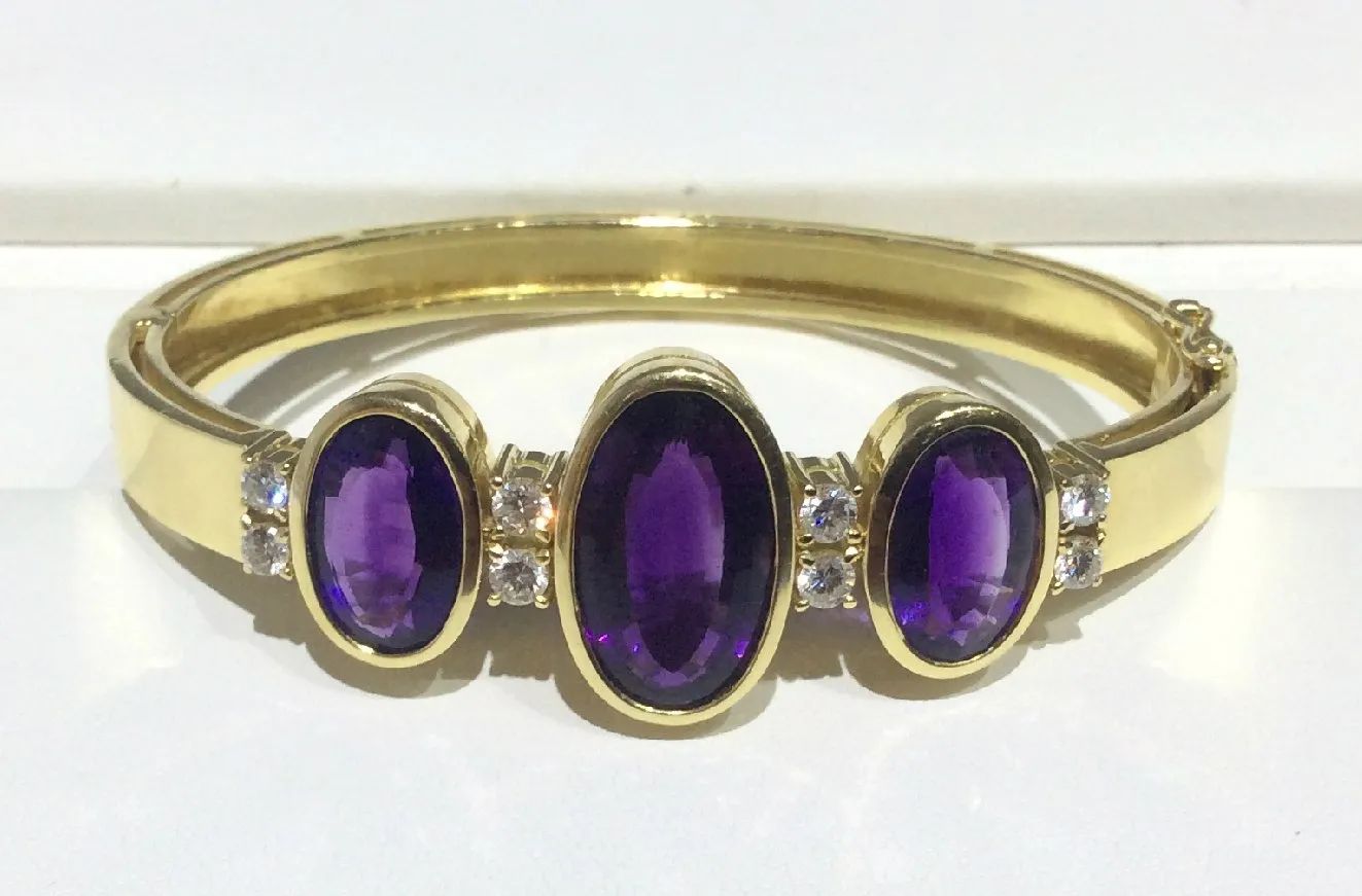 a gold ring with purple stones and diamonds