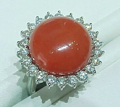 a ring with a red stone and diamonds on it