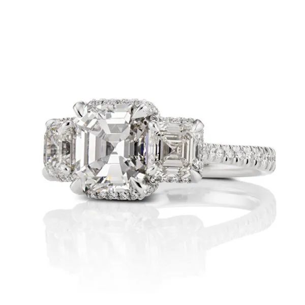 a white gold ring with an emerald cut diamond in the center surrounded by smaller diamonds
