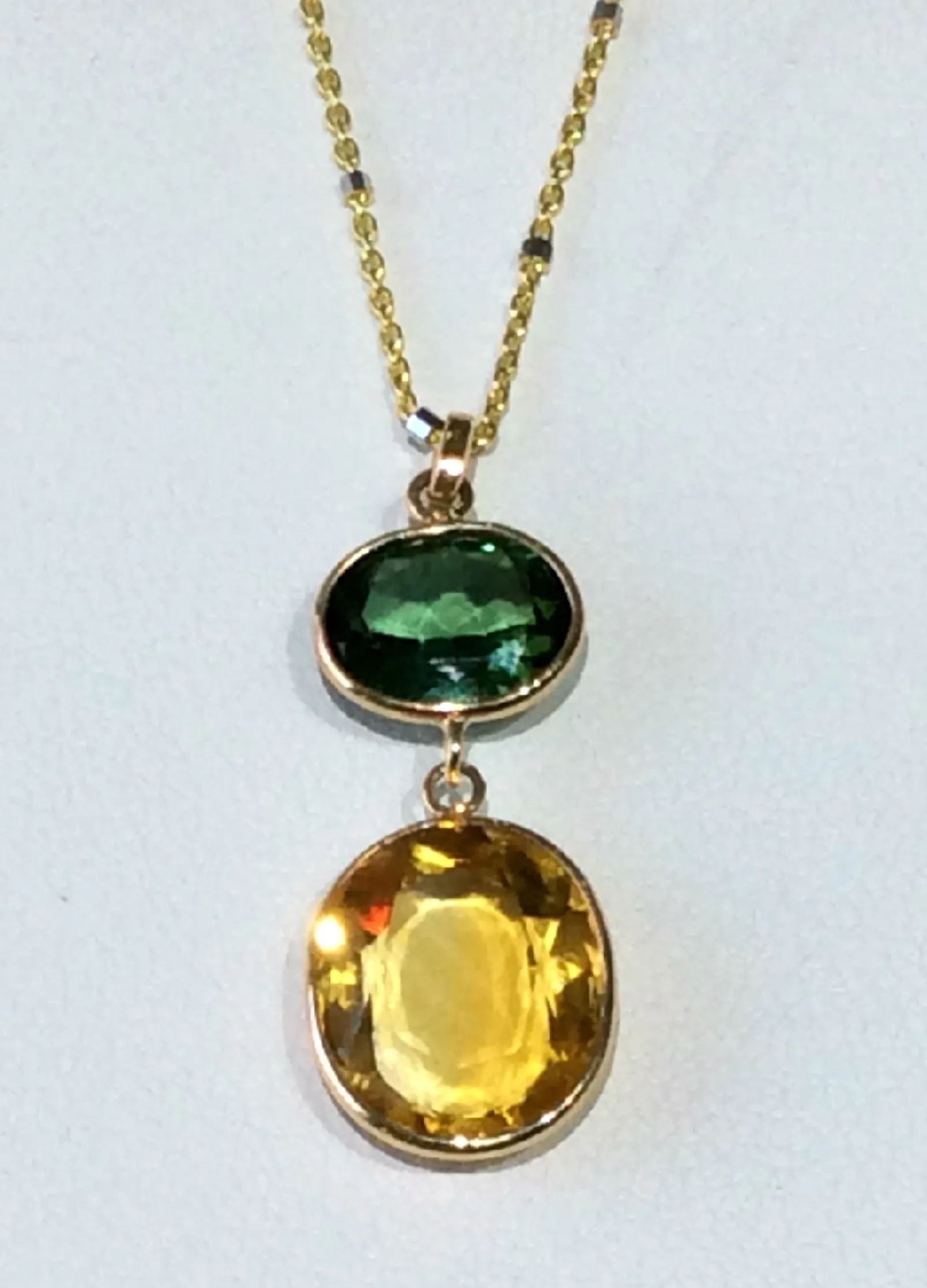a necklace with a green stone and a yellow stone