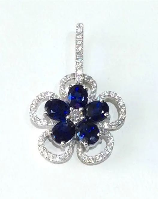 a flower shaped pendant with blue sapphires and white diamonds